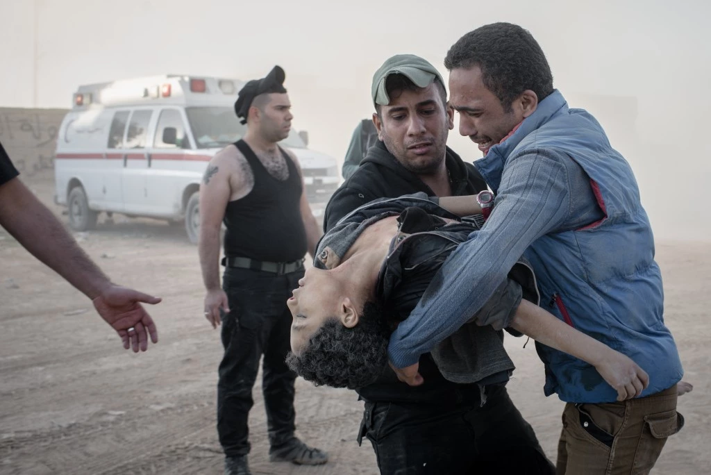 A man hands his younger brother, killed by an IED, to a medic at a field clinic in the Samah neighborhood of Mosul, Iraq on Nov. 18, 2016.
