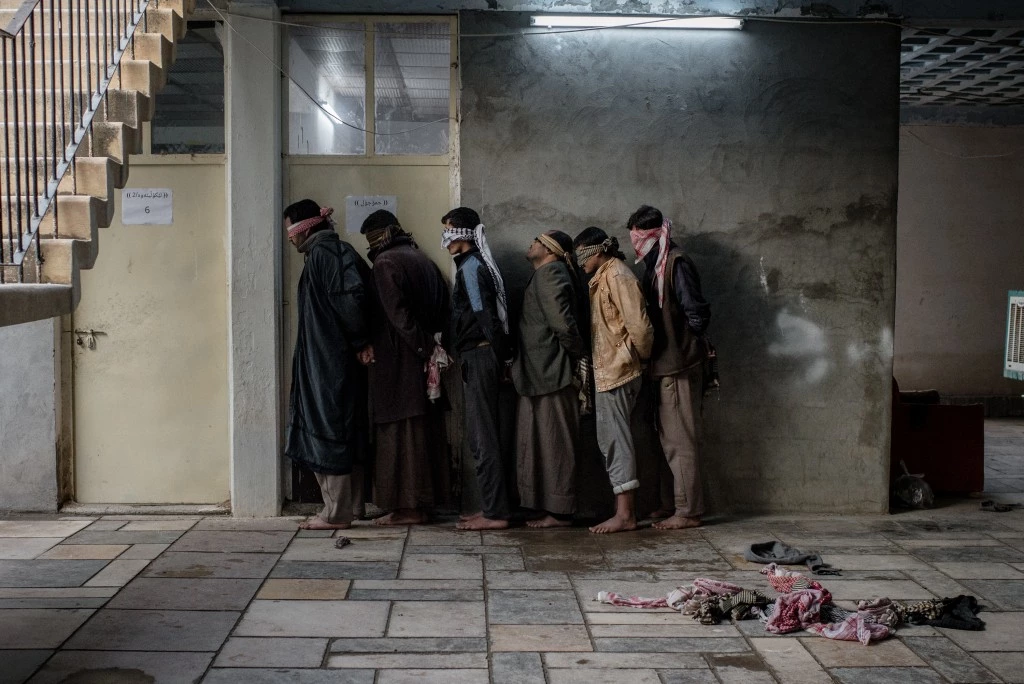 Newly displaced civilians from Hawija wait outside an interrogation room in a base run by Asayish, Kurdish Regional Government security forces, in Dibis, Iraq on Dec. 12, 2016.