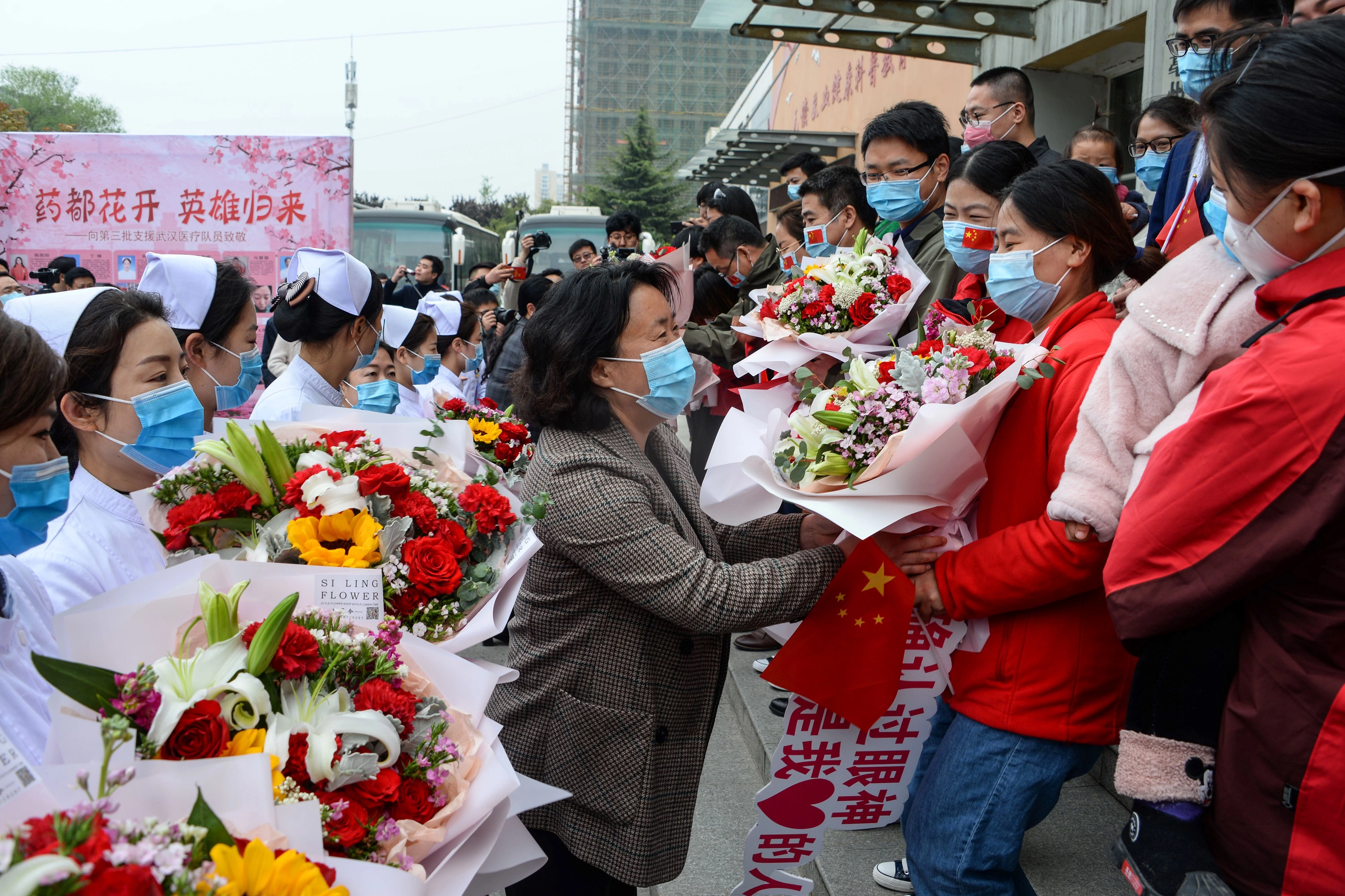 Após ajudarem no esforço de combate à covid-19 em Wuhan, membros da equipe médica recebem flores ao voltar para casa em Bozhou, na província chinesa de Anhui, em 10 de abril de 2020.