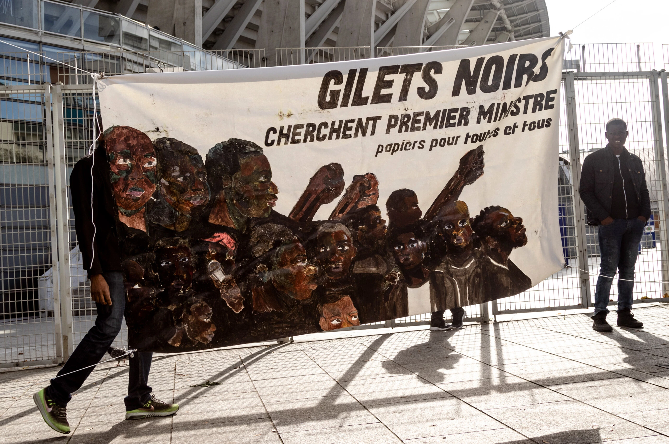 Os manifestantes carregam um cartaz onde se lê "Coletes Negros procuram primeiro-ministro. Documentos para todos" em um protesto na frente do Estádio Charlety, em 11 de outubro de 2019.