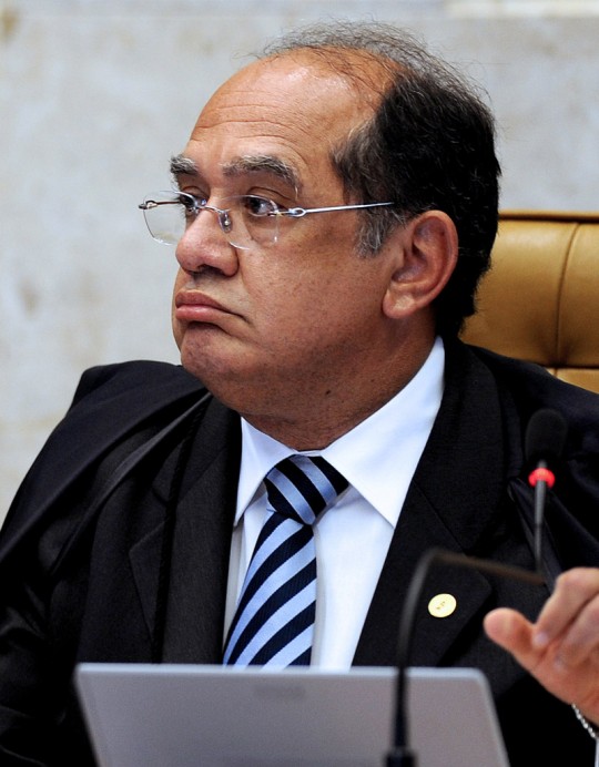 Brazilian Supreme Court President Gilmar Mendes speaks during the trial of Italian Cesare Battisti in Brasilia, on November 18, 2009.  Brazil's Supreme Court is to resume on Wednesday its weighing of an extradition demand for an Italian ex-militant, with the outcome potentially creating a constitutional clash of powers. The court so far is evenly split on the case of whether to send Cesare Battisti, 54, back to Italy to serve a life sentence for murders committed in the 1970s.  A vote by chief justice Gilmar Mendes is to break a 4-4 deadlock among his colleagues.  The placards read "To Extradite Cesare Is To Modernize The Inquisition".  AFP PHOTO/Evaristo SA (Photo credit should read EVARISTO SA/AFP/Getty Images)