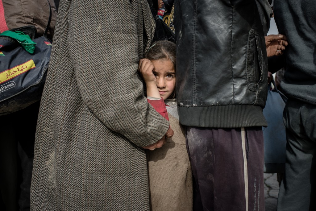 People fleeing fighting between Iraqi forces and ISIS line up to board a truck headed for an displaced persons camp southwest of Mosul, Iraq on March 1, 2017.