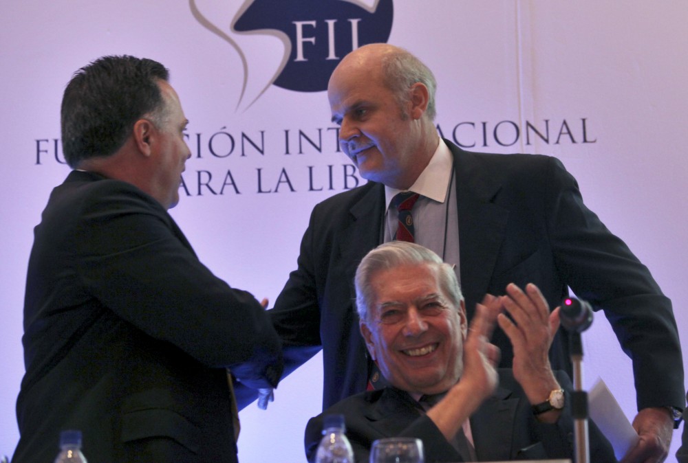 Alejandro Chafuen, of the Atlas Economic Research Foundation, back right, shakes hands with Rafael Alonzo, of Venezuela's Freedom Center for Economic Studies, CEDICE, left, as Peruvian writer Mario Vargas Llosa applauds during the opening of the "Freedom and Democracy" international forum in Caracas, Thursday, May 28, 2009.(AP Photo/Ariana Cubillos)