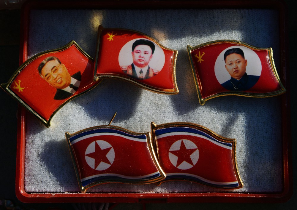 Badges showing late North Korean leaders (L-R) Kim Il Sung and Kim Jong Il and new leader Kim Jong-Un for sale by a street vendor in the Chinese border town of Dandong on the second anniversary of the death of former leader Kim Jong-Il, December 17, 2013. North Korean leader Kim Jong-Un presided over a major remembrance ceremony on the second anniversary of the death of his father and former leader Kim Jong-Il. The meeting came days after the shock execution of Kim Jong-Un's uncle and one-time political mentor, Jang Song-Thaek -- a purge that raised questions about the stability of the current regime in Pyongyang. AFP PHOTO/Mark RALSTON (Photo credit should read MARK RALSTON/AFP/Getty Images)