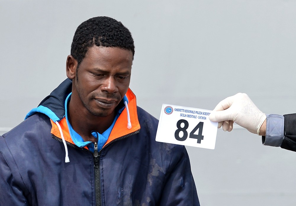 Italian police officers identify a migrant suspected to be a smuggler after disembarking off the Italian Guardia Costiera vessel Fiorillo at the Sicilian harbour of Catania on April 24, 2015. EU leaders gathered in Brussels on April 23 considered launching a military operation against human traffickers in Libya, in a bold effort to halt the deadly flow of refugees trying to reach Europe by sea. AFP PHOTO / ALBERTO PIZZOLI (Photo credit should read ALBERTO PIZZOLI/AFP/Getty Images)