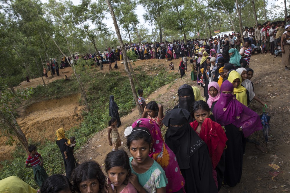 KUTUPALONG, BANGLADESH - OCTOBER 7: Rohingya wait in line for hours as an emergency food distribution takes place by World Food program ( WFP) and Save The Children October 7, Kutupalong, Cox's Bazar, Bangladesh. Rice, lentils, sugar, salt and oil was given out. Well over half a million Rohingya refugees have fled into Bangladesh since late August during the outbreak of violence in Rakhine state causing a humanitarian crisis in the region with continued challenges for aid agencies. (Photo by Paula Bronstein/Getty Images)