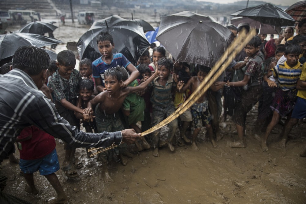 THAINKHALI, BANGLADESH - OCTOBER 7: A man hits anxious Rohingya children with a cane as things get out of control during a humanitarian aid distribution while monsoon rains continue to batter the area causing more difficulties October 7, Thainkhali camp, Cox's Bazar, Bangladesh. Well over half a million Rohingya refugees have fled into Bangladesh since late August during the outbreak of violence in Rakhine state causing a humanitarian crisis in the region with continued challenges for aid agencies. (Photo by Paula Bronstein/Getty Images)