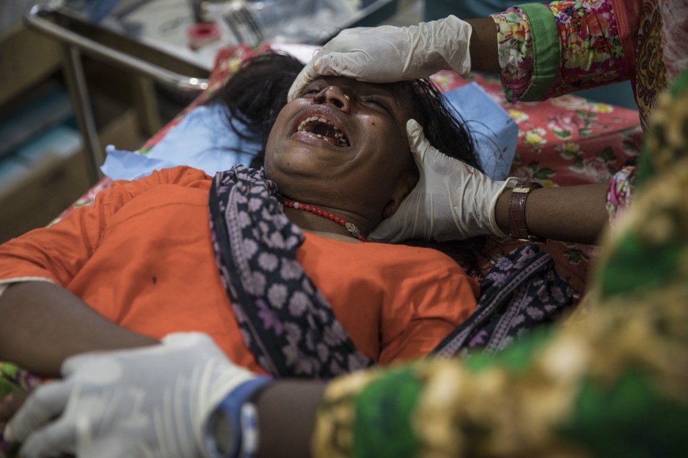 KUTUPALONG, BANGLADESH - OCTOBER 4: Aneta Begum,25, is treated for a head injury by staff member Jacqueline Murekezi at the 'Doctors Without Borders' Kutupalong clinic on October 4, 2017 in Cox's Bazar, Bangladesh. Doctors Without Borders has been providing comprehensive basic healthcare services at their Kutupalong clinic since 2009. Due to the current Rohingya crisis, the clinic has expanded it's inpatient capacity dealing with approximately 2,500 out patient treatments and around 1,000 emergency room patients per week. All healthcare services provided at the clinic are free of charge to both the Rohingya refugee population as well as local Bangladeshi patients. Doctors Without Borders has also set up a number of health posts, mobile clinics and water and sanitation services elsewhere in Cox's Bazar to better respond to the influx. Well over a half a million Rohingya refugees have fled into Bangladesh since late August during the outbreak of violence in Rakhine state causing a humanitarian crisis in the region with continued challenges for aid agencies. (Photo by Paula Bronstein/Getty Images)